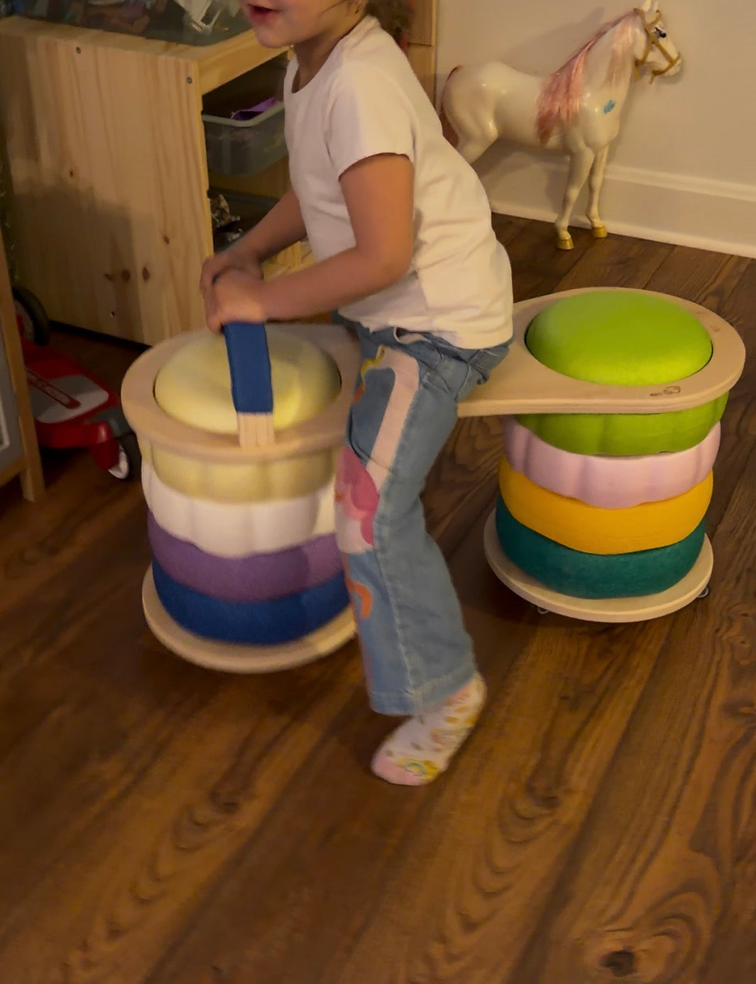 Child playing with a colorful wooden scooter being used with stepping stones