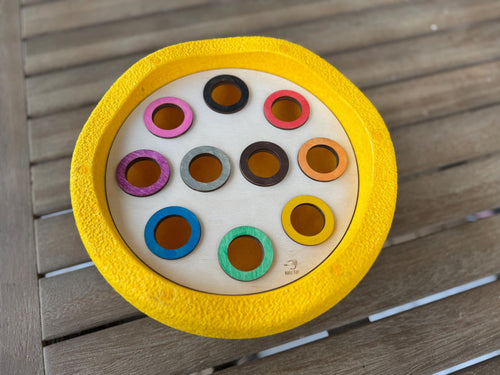 A wooden lid with colorful holes inside Stapelstein stepping stone 
